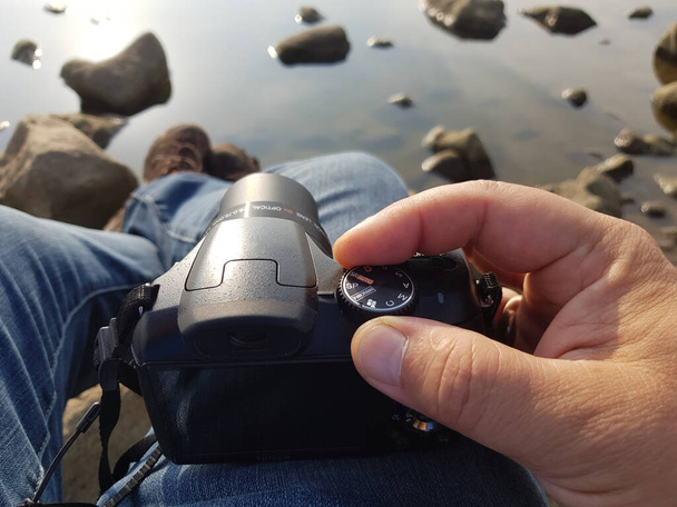 ρύθμιση της κάμερας πριν από γυρίσματα σε μια λίμνη με μια βραχώδη ακτή - Φωτογραφία, εικόνα