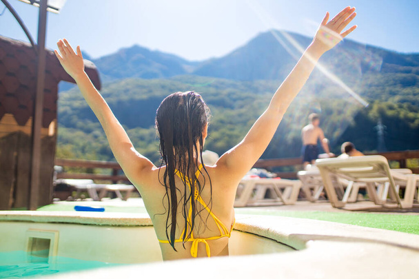 woman in the pool looking at mountain landscape.Enjoying beautiful mountains - Photo, Image