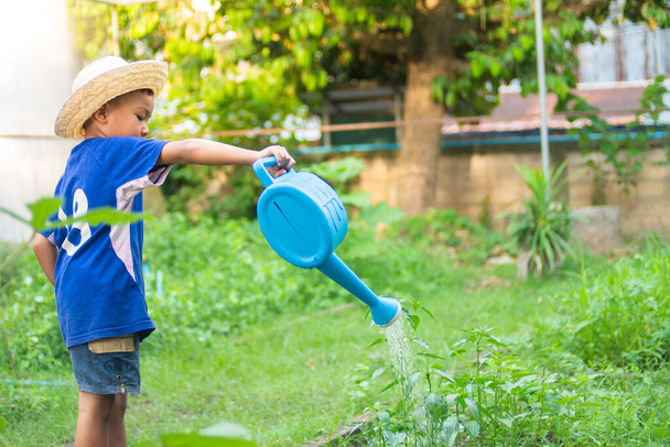 Porträtbild eines asiatischen Bauernkindes, das das Gemüse auf dem Gartenbauernhof gießt. 5 Jahre alt des Kindes. Lern- und Landwirtschaftskonzept für Kinder.  - Foto, Bild