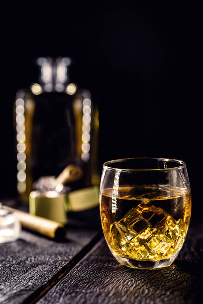 sklenice whisky s ledem a doutníkem, se zapalovačem v pozadí. Kouření a relaxace koncept, drahé nápoje - Fotografie, Obrázek