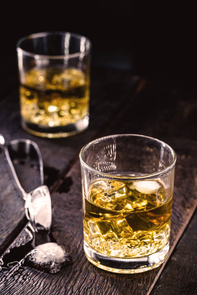 whiskey of bourbon, gedistilleerde drank met mout in glas met ijsblokjes, op geïsoleerde zwarte ondergrond. - Foto, afbeelding