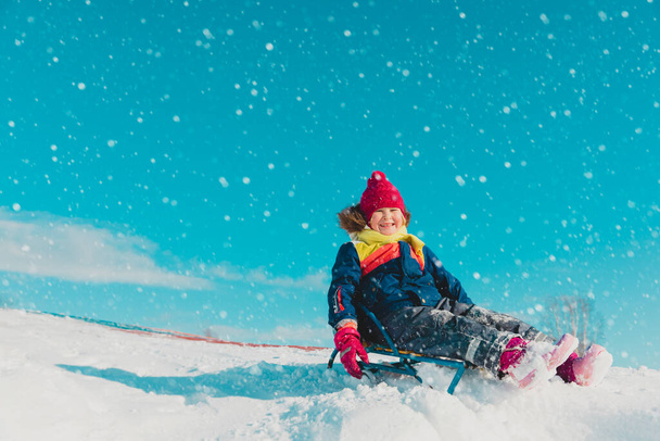 glückliches kleines Mädchen auf dem Schlitten in der winterlichen Natur - Foto, Bild