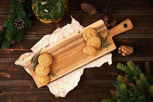 Wooden background, craft paper, cookies, herbal tea and spruce branches, holiday composition - Photo, Image