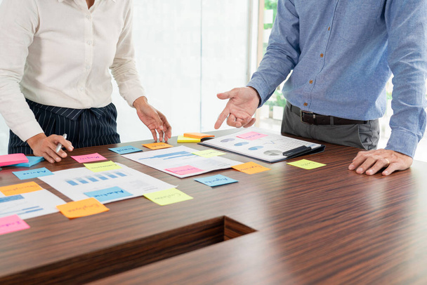 ビジネスの創造的なグループブレインストーミングは、テーブルの決定に関するアイデアを共有するために粘着ノートピッキングを使用していますビジネス会議室で計画を開発するための概念の選択 - 写真・画像