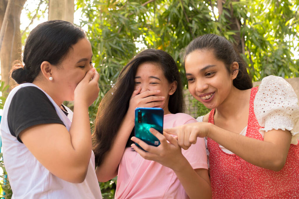 Tres mejores amigos se ríen de un post o foto en las redes sociales. Concepto de amistad. - Foto, Imagen