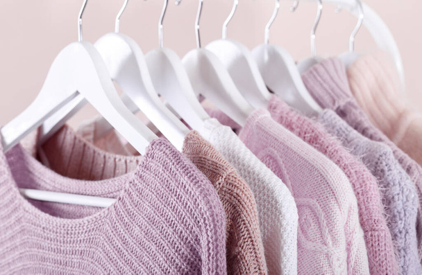 Quente de malha, outono, roupas de inverno penduradas em um rack, conceito de tendências, cores pastel - Foto, Imagem