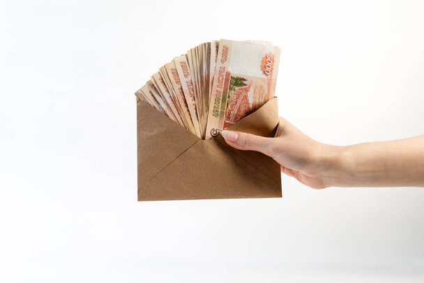 Nielegalna pensja. Kobieta trzyma kopertę z pieniędzmi. Widok z boku, zbliżenie. Białe tło. Koncepcja światowego dnia walki z korupcją. - Zdjęcie, obraz