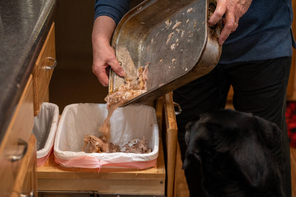 Жінка викидає кістки приховують сміття подяки індички, в смітник
 - Фото, зображення
