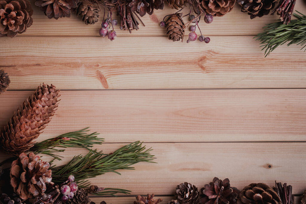  Vánoční kornouty s věnečkem hranice na dřevěném pozadí. Strom větev s borovicovými kužely na dřevě. Zimní pozadí s kopírovacím prostorem. Horní pohled. Plocha - Fotografie, Obrázek