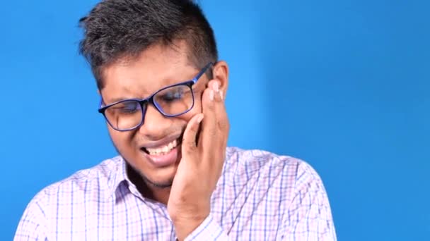 νεαρός άνδρας με ευαίσθητα δόντια σε μπλε φόντο  - Πλάνα, βίντεο