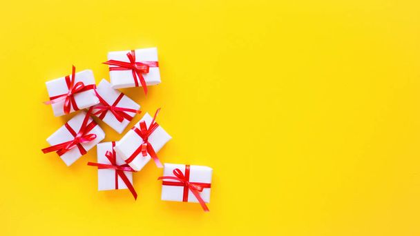 Few gift boxes with red tape on yellow background. Holiday concept. Top view - Fotoğraf, Görsel