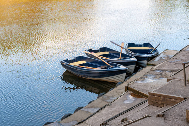 Three blue and white rowing boats moored on a tranquil river on a sunny day. - Photo, Image