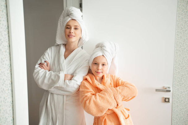 beautiful mom with daughter in bathrobes indoors - Foto, Imagen