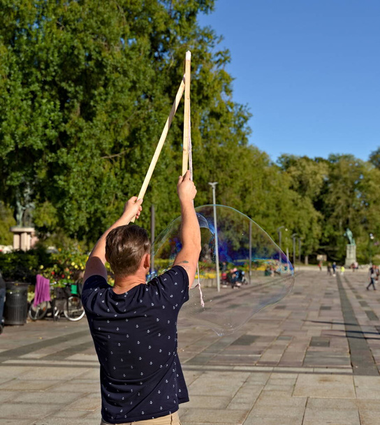 Artista de rua soprando bolhas de sabão gigantes em um parque em um dia de verões.  - Foto, Imagem