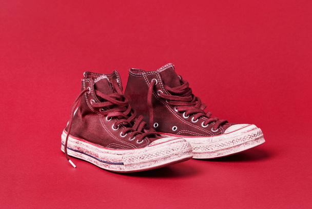 Μεταχειρισμένα παπούτσια καμβά σε κόκκινο φόντο - Φωτογραφία, εικόνα