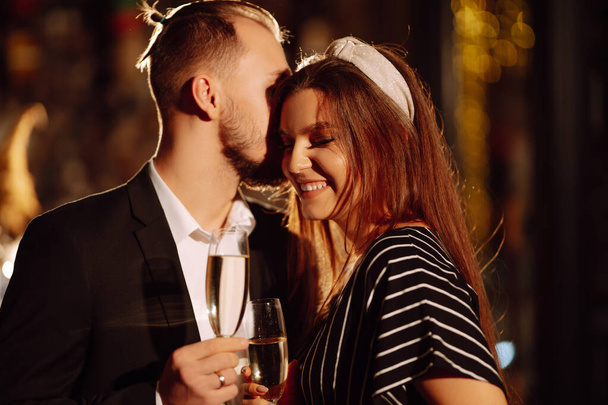 Young happy couple in love toasting with champagne on the bar. Smiling man and woman clinking a glass champagne, enjoying winter holiday. Party, celebration, drink, birthday concept. - Foto, Imagem