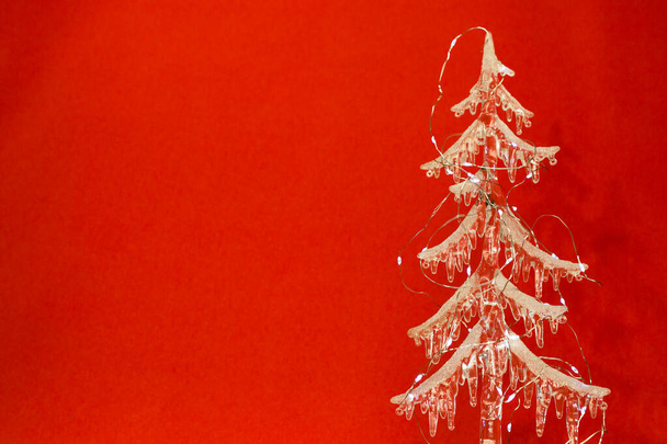 New Year and Christmas card on a red background. Transparent Christmas tree made of icicles and Christmas lights. - Foto, immagini
