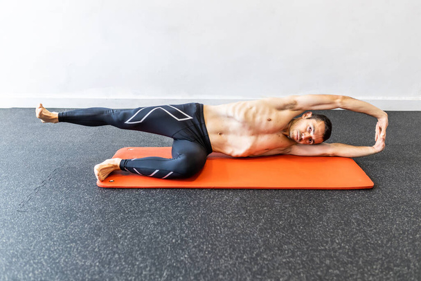 Kaukasischer junger erwachsener Mann trainiert hypopressive Bauchübungen auf der Matte - Foto, Bild