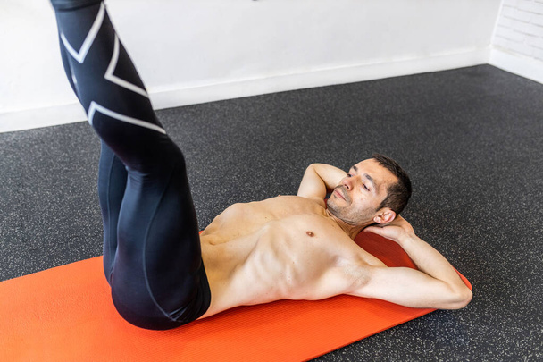 homem adulto jovem caucasiano treinando exercícios abdominais hipopressivos no tapete - Foto, Imagem
