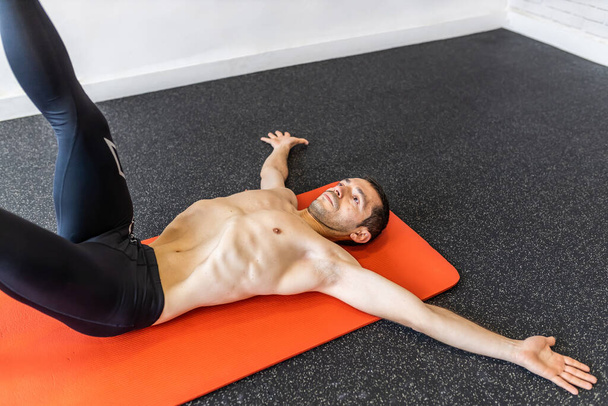 Kaukasischer junger erwachsener Mann trainiert hypopressive Bauchübungen auf der Matte - Foto, Bild