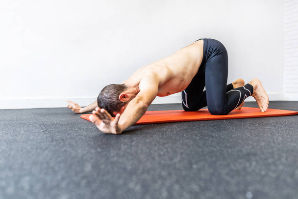 Kaukasische jonge volwassen man training hypopressieve abdominale oefeningen op de mat - Foto, afbeelding