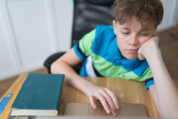 Caucasian boy is bored and tired during his online classes - Fotoğraf, Görsel