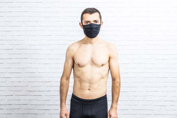 Καυκάσιος άνδρας με μάσκα προσώπου που εκπαιδεύει καταπιεστικές κοιλιακές ασκήσεις στο χαλάκι - Φωτογραφία, εικόνα