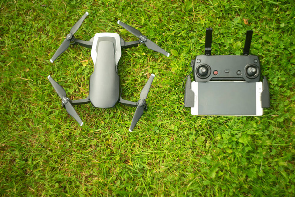 Copter and remote control with phone on the green grass in the Park - Photo, Image