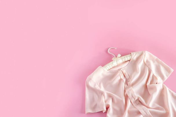 Pink woman blouse is hanging on beautiful hanger on pink background with copy space. Sale and shopping concept. - Photo, Image