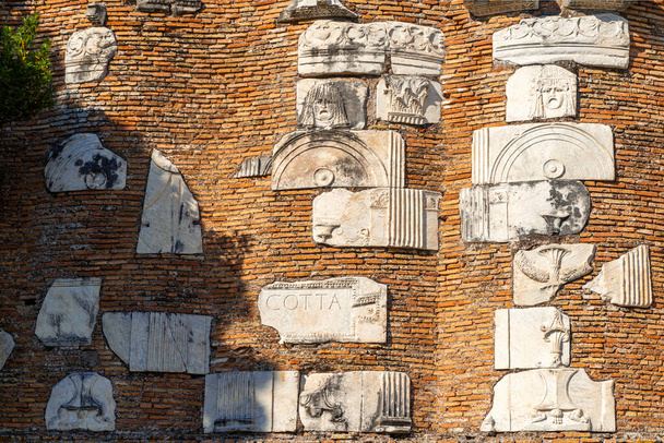 Detalle del mausoleo de ladrillo de Casal Rotondo, Appia Antica. En relieve decoraciones de mármol de máscaras, decoraciones florales, inscripciones, piezas de arquitectura romana en un día de sol y nubes. Roma - Foto, imagen