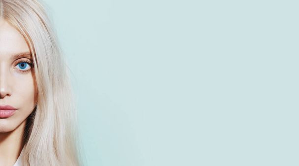 Half face portrét mladé blondýny dívka na azurovém pozadí s kopírovacím prostorem. - Fotografie, Obrázek