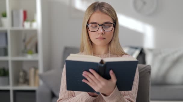 Woman in eyeglasses reading book - Materiał filmowy, wideo