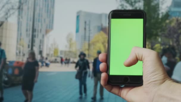 Gros plan de la main de l'homme en utilisant un smartphone à l'extérieur avec écran vert vide. 4K - Séquence, vidéo