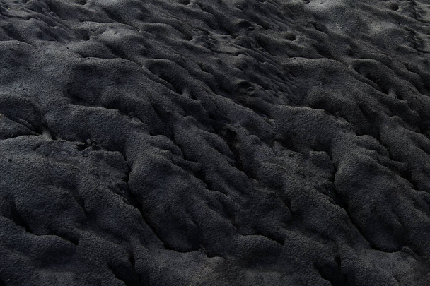 Ciemny piasek z nieregularnymi formacjami, ze względu na czas i naturę. - Zdjęcie, obraz