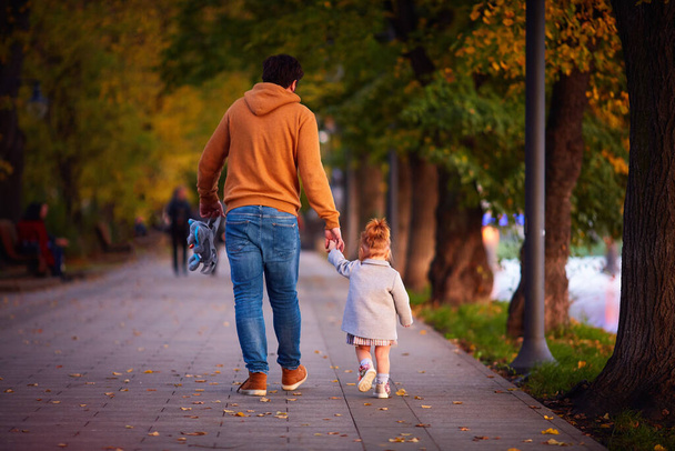 rear view of father with baby girl on the walk on the autumn street - Фото, изображение