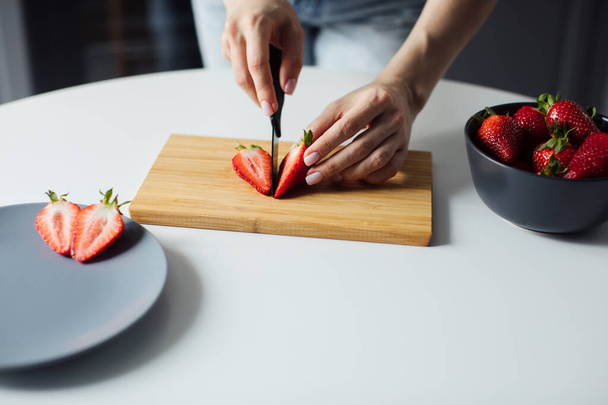 イチゴを切る女の子の手のクローズアップ。健康食品 - 写真・画像