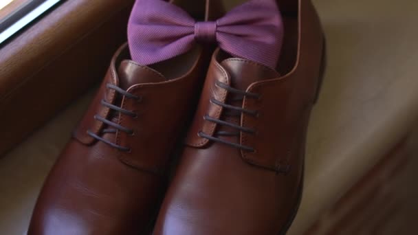 brown leather shoes and the grooms bow tie stand on the windowsill while getting ready - Footage, Video