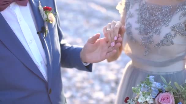 el novio sostiene la mano de las novias, la novia tiene un anillo en su dedo - Imágenes, Vídeo