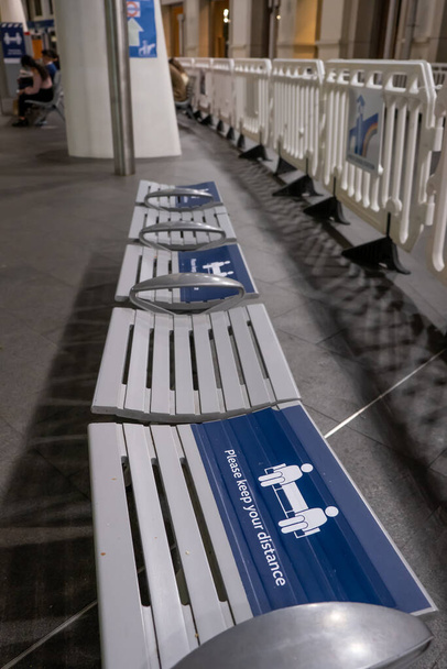 A row of seats with signs on alternating chairs asking people to social distance because of the Coronavirus pandemic - Photo, Image