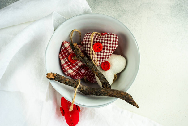 St. Valentine Day concept with place setting, ceramic bowl full of  vintage textile hearts on concrete background - Foto, Imagem