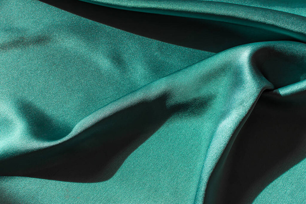 Green satin fabric pleats close-up. Abstract trend background of the 2021 Tidewater Green color.Luxury elegant bright texture with hard light with copyspace.Banner design for Christmas,Valentine's day - Valokuva, kuva