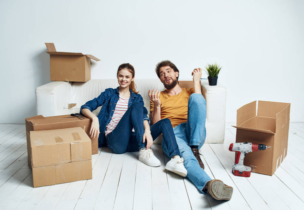 mudanza renovación feliz hombre y mujer en el suelo en un nuevo apartamento con cajas - Foto, Imagen
