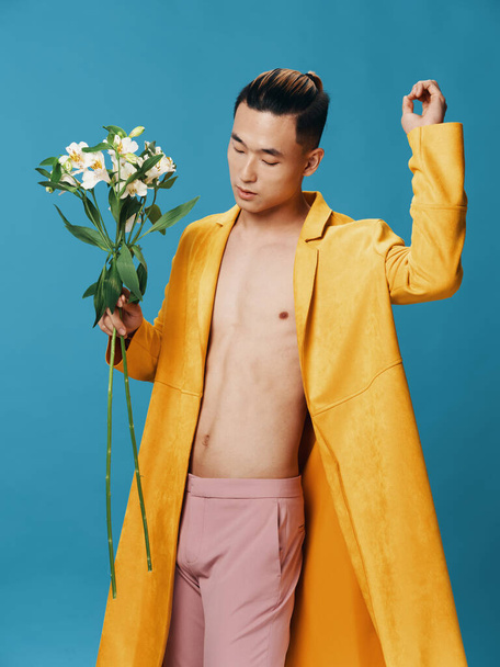 Hombre romántico con un ramo de flores sobre un fondo azul Modelo asiático  - Foto, Imagen