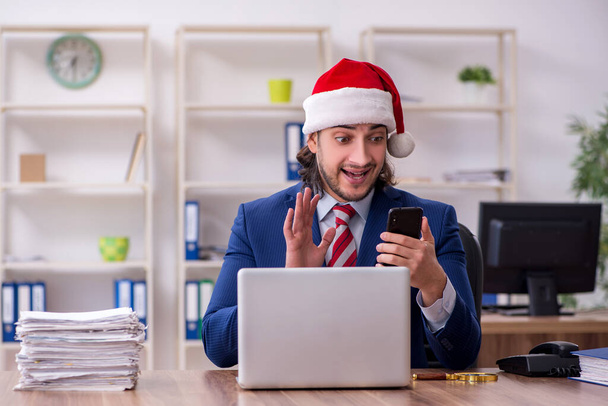 Jeune employé masculin travaillant dans le bureau à la veille de Noël - Photo, image