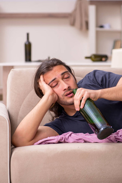 Young unemployed man drinking alcohol at home - Foto, Imagen