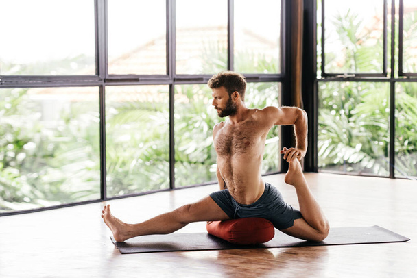 Yoga men workout in studio in front of a window - 写真・画像