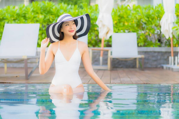 Porträt schöne junge asiatische Frau entspannen Lächeln um Freibad in Hotel Resort fast Meer Strand Ozean - Foto, Bild