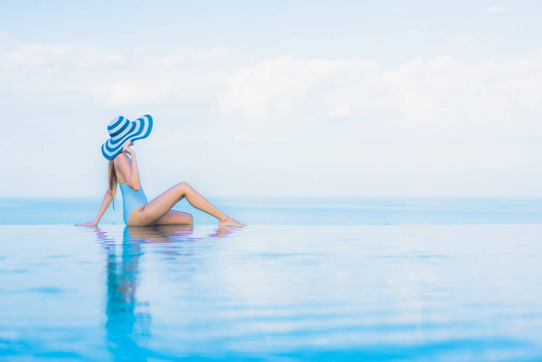 Retrato hermosa joven mujer asiática relajarse sonrisa alrededor de la piscina al aire libre en el complejo hotelero casi mar playa océano - Foto, Imagen