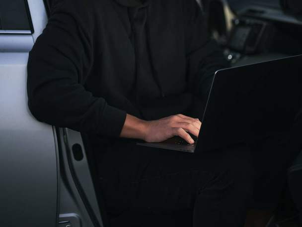 entrepreneur using laptop in car. low key photo without a face - Foto, afbeelding