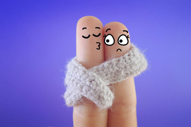 Δύο δάχτυλα είναι διακοσμημένα ως δύο άτομα. Μοιράζονται ένα κασκόλ όταν βγαίνουν ραντεβού.. - Φωτογραφία, εικόνα